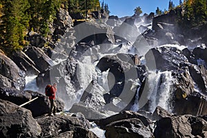 Happy man with backpack enjoying amazing waterfall Travel Lifestyle and success concept vacations into the wild nature