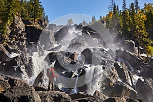 Happy man with backpack enjoying amazing waterfall Travel Lifestyle and success concept vacations into the wild nature