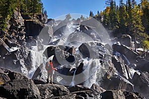 Happy man with backpack enjoying amazing waterfall Travel Lifestyle and success concept vacations into the wild nature