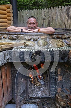 Happy man bathing in the cast iron vat with mineral water containing hydrogen sulphide. Water in cast iron vats heated to 40-45