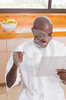 Happy man in bathrobe reading newspaper photo