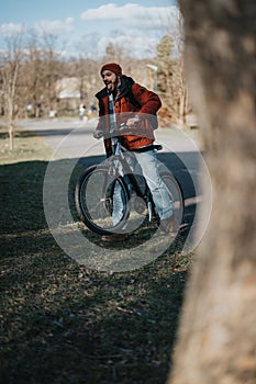 Happy man with a beard enjoying a sunny day while cycling in the park