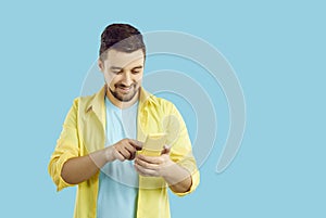 Happy man on blue copy space background messaging or making call on mobile phone