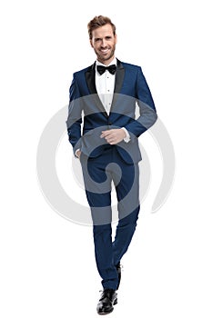 Happy man in blue tuxedo walking with hand in pocket