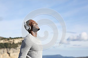 Happy man breathing listening to music outdoors