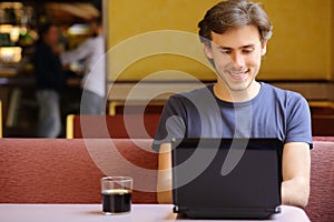 Happy man browsing internet on a laptop in a restaurant photo