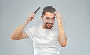 Happy man brushing hair with comb over gray