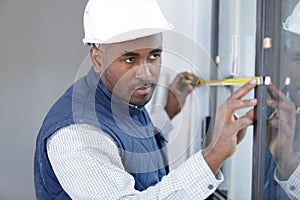 happy man builder infront window with tape measure