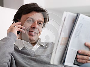 Happy man buying from catalogue with telephone