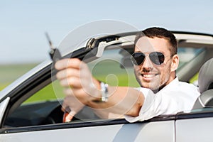 Happy man in cabriolet showing car key