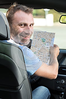 happy man in car with paper roadmap