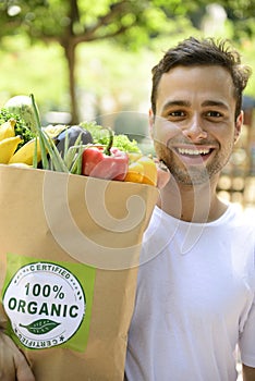 Happy man carrying a bag of organic food.