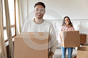 Happy man carrying box moving into new house with girlfriend