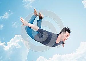 Happy man in casual clothes, flying in the sky, around a cloud. The concept of travel