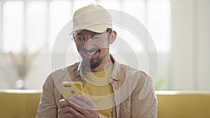 Happy man celebrating mobile win uses phone at home. Man reading good news, victory sitting on couch