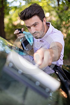 happy man cleaning car window photo
