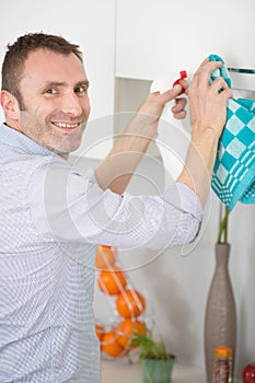 Happy man cleaning table with rag in kitchen