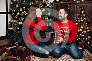 Happy man covering his girlfriend`s eyes at Christmas.