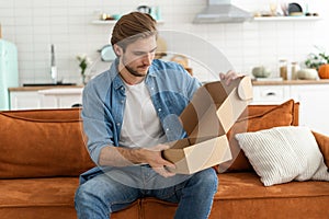 Happy man customer unpacking cardboard box receive open post mail delivery package