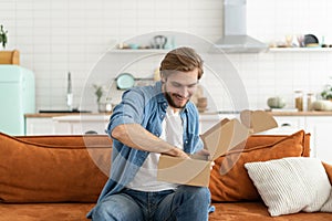 Happy man customer unpacking cardboard box receive open post mail delivery package