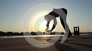 Happy man dances on his arms on a river bank in summer in slo-mo