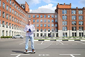 Happy man with documents rides gyroscooter near photo