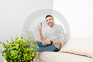 Happy man doing internet shopping and holding credit card