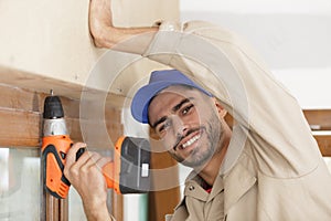 happy man drilling hole in window frame