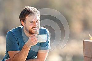 Happy man drinking and contemplating views outdoors