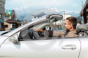 Happy man driving cabriolet car over city in japan