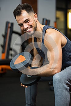 happy man with dumbbells flexing muscles in gym