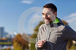 Happy man with earphones running in city