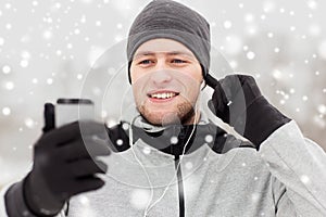 Happy man with earphones and smartphone in winter