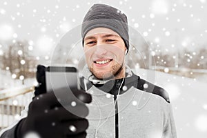 Happy man with earphones and smartphone in winter