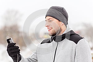 Happy man with earphones and smartphone in winter