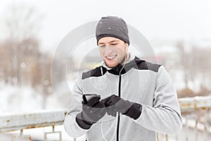 Happy man with earphones and smartphone in winter