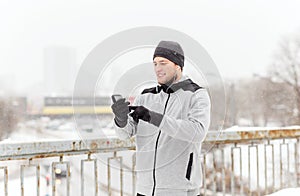 Happy man with earphones and smartphone in winter