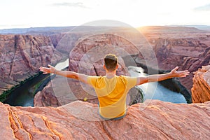 Happy man on the edge of the cliff. Horseshoe Bend Canyon in Page, Arizona. Adventure and tourism concept