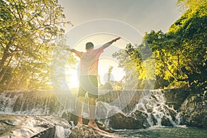 Happy man enjoying amazing tropical waterfall raised hands Travel Lifestyle and success concept vacations