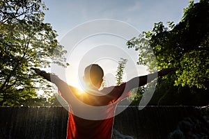 Happy man enjoying amazing tropical waterfall raised hands Travel Lifestyle and success concept vacations