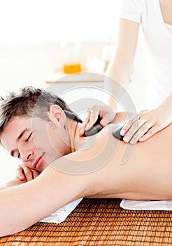 Happy man enjoying a back massage with hot stones