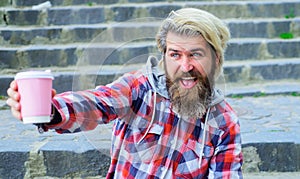 Happy man Enjoying coffee outdoor. Bearded guy in casual wear with paper cup of morning coffee.