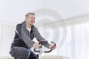 Happy man exercising on a spin bike at home