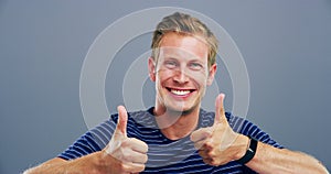 Happy man, face and thumbs up for winning, good job or success isolated against a studio background. Portrait of young