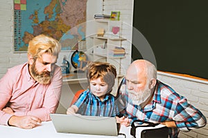Happy man family using notebook together. Son teaching father and mature senior grandfather to use laptop computer.