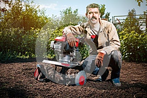 Happy man Farmer plows the land with a cultivator, preparing it