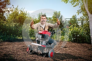 Happy man Farmer plows the land with a cultivator, preparing it