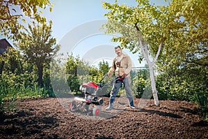 Happy man Farmer plows the land with a cultivator, preparing it