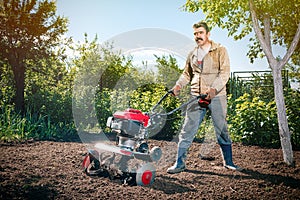 Happy man Farmer plows the land with a cultivator, preparing it