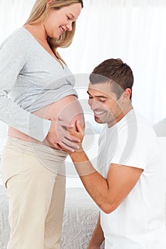 Happy man feeling the belly of his pregnant wife